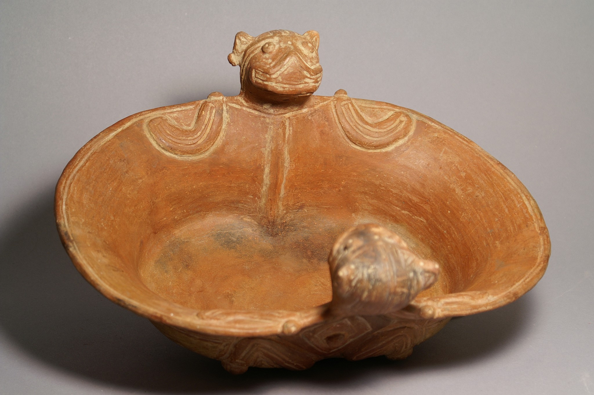 Colombia, Tairona Ceramic Tray with Bat Adornos
A redware ceramic tray embellished with two smiling bats with outstretched wings.  The head and the body of the bat are decorated with incised lines, the back with a diamond-shaped motif. The outer wall of the bowl is incised with squarish scroll designs.
Media: Ceramic
Dimensions: L:  13", W:  10-1/2"
$8,000
94271
