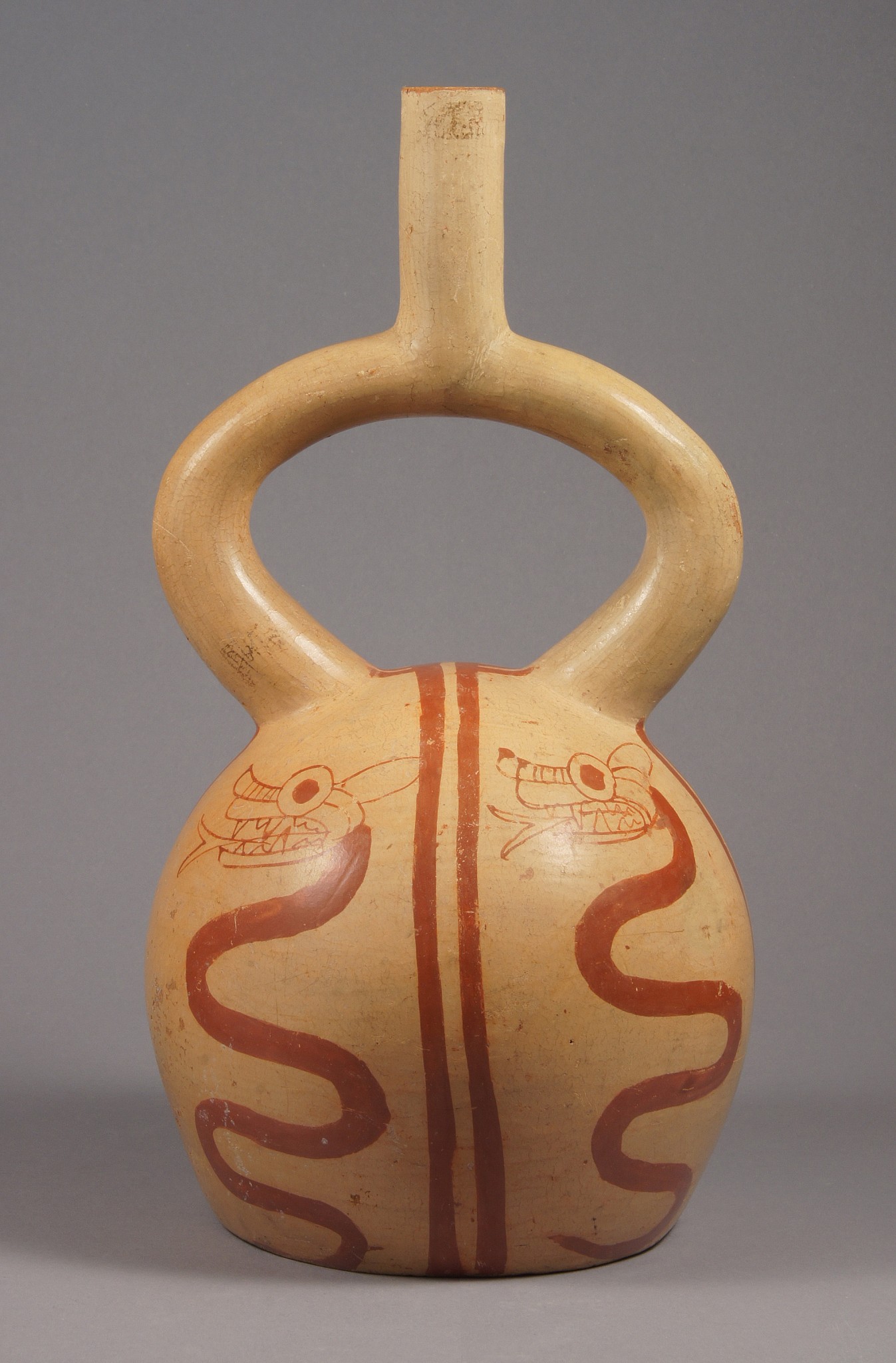 Peru, Moche IV fine line ceramic stirrup spout vessel of Serpents
A large stirrup spout vessel painted with four undulating serpents facing upwards, one in each quadrant in red/brown on a beige ground.  The serpent represents rebirth, the shedding of its skin repeating as much as four times, perhaps for each season. Stirrup spout vessels were used  to hold  ceremonial corn beer and the spout allowed  the air to enter one channel while the liquid was able to pour  through the other channel.
Media: Ceramic
Dimensions: Height 11 1/2"
$4,500
90078