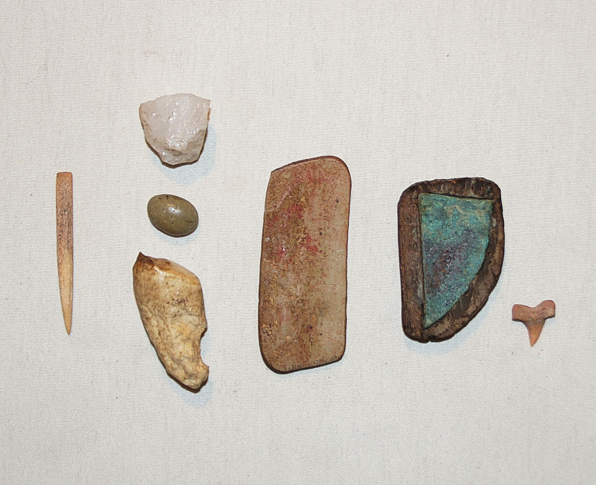 Chile, Tools for Chipping and Cutting with Copper Blade in Wood Case
These tools were found in a fisherman's burial.  The set inclueds: a bone awl for marking, a bone napping stone for arrow heads, a smooth green stone for hammering, a stone crystal for sharpening copper hooks, a flat rectangular stone for sharpening hooks, a copper blade in its wood case and a small sharks tooth for inscribing.
Media: Stone
Dimensions: Length 1. 8”
N6015