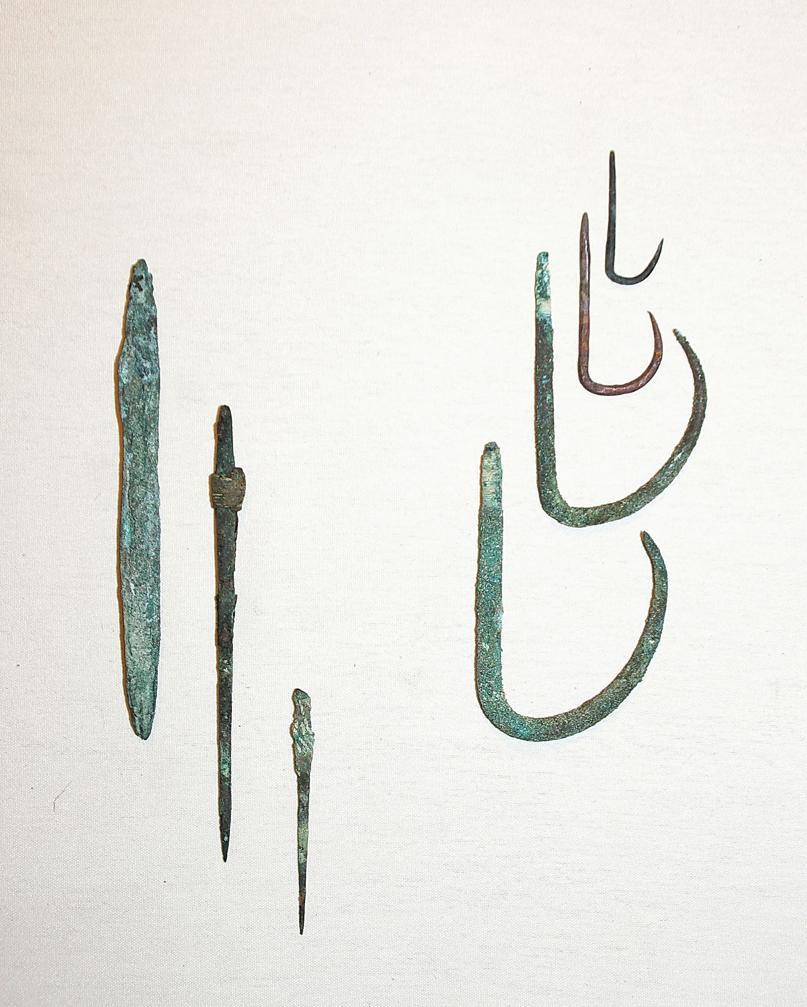 Chile, Copper Spear Tips and Fish Hooks
These copper spear points have traces of the original cotton line .  The sharp points were fitted into a slender wooden shaft in order to spear small fish. The large copper fishhooks are for large mouthed fish.
Period: Chile, Arica, formative period, c. 1000 BC - AD 300
Media: Metal
Dimensions: Lengths Vary: 1.5â€ - 5.5â€
N6018