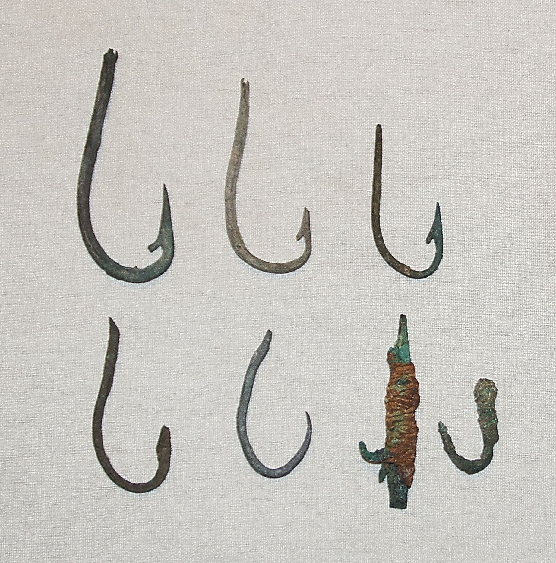 Chile, Late Copper Fish Hooks with Barbs
These barbs were made by hammering and chiseling the copper hooks.  One hook demonstrates how a line was attached to the hook by tying a copper strip around the shaft so it would not slide off.
Period: Chile, Arica, formative period, c. 1000 BC - AD 300
Media: Metal
Dimensions: Lengths Vary: 1.50" - 2.5â€
N6024