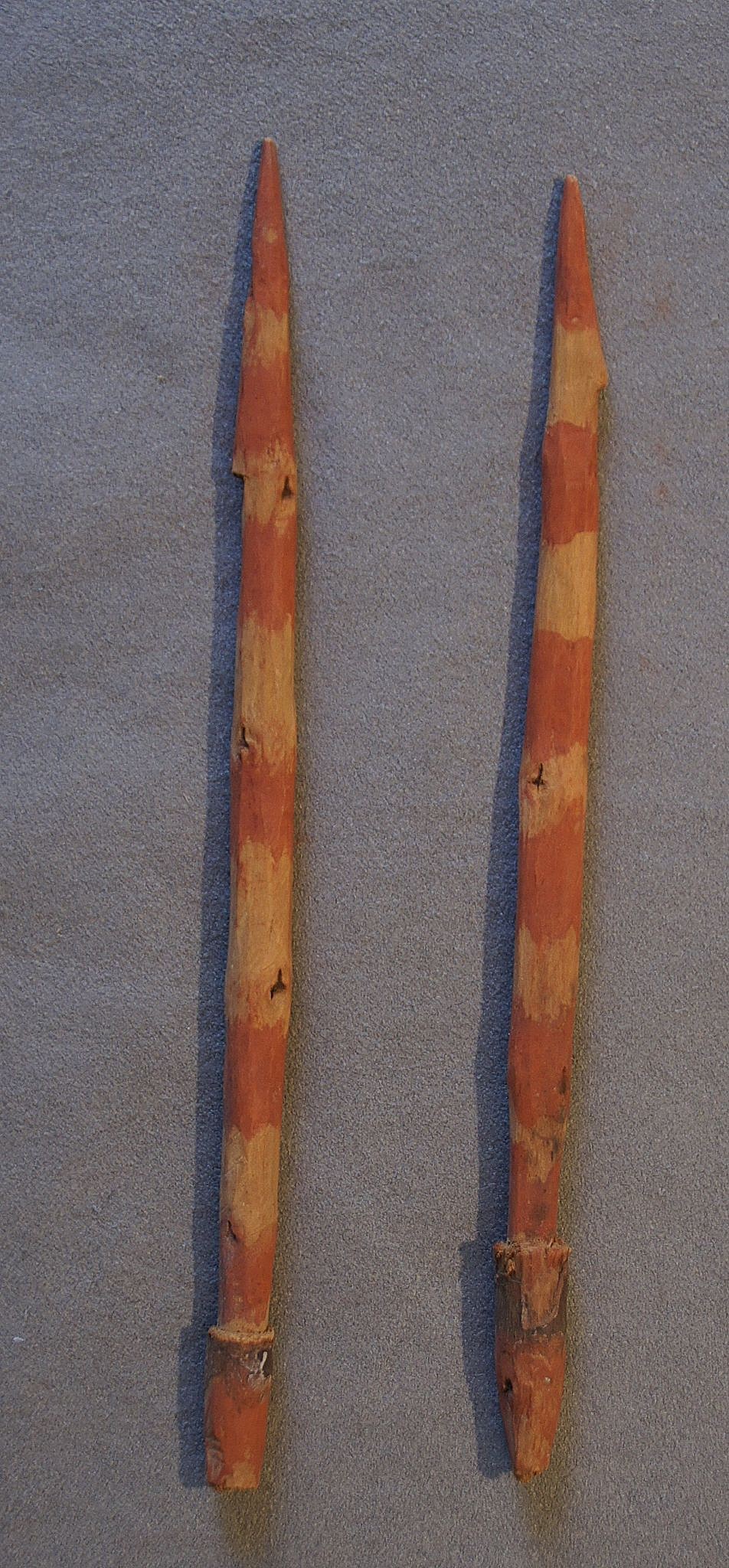 Chile, Two Early Carved Wooden Harpoon Points Painted with Red Stripes
These solid harpoon points are carved with a pointed tip and a notch to serve as a barb.  The opposite end is tapered to fit into a socketed throwing stick.  The red paint was usually used for items that were intended for use in the afterlife.
Period: Chile, Camaroni, North Coast, c. 100 - 600 BC
Media: Wood
Dimensions: Length: 7"
n6029
