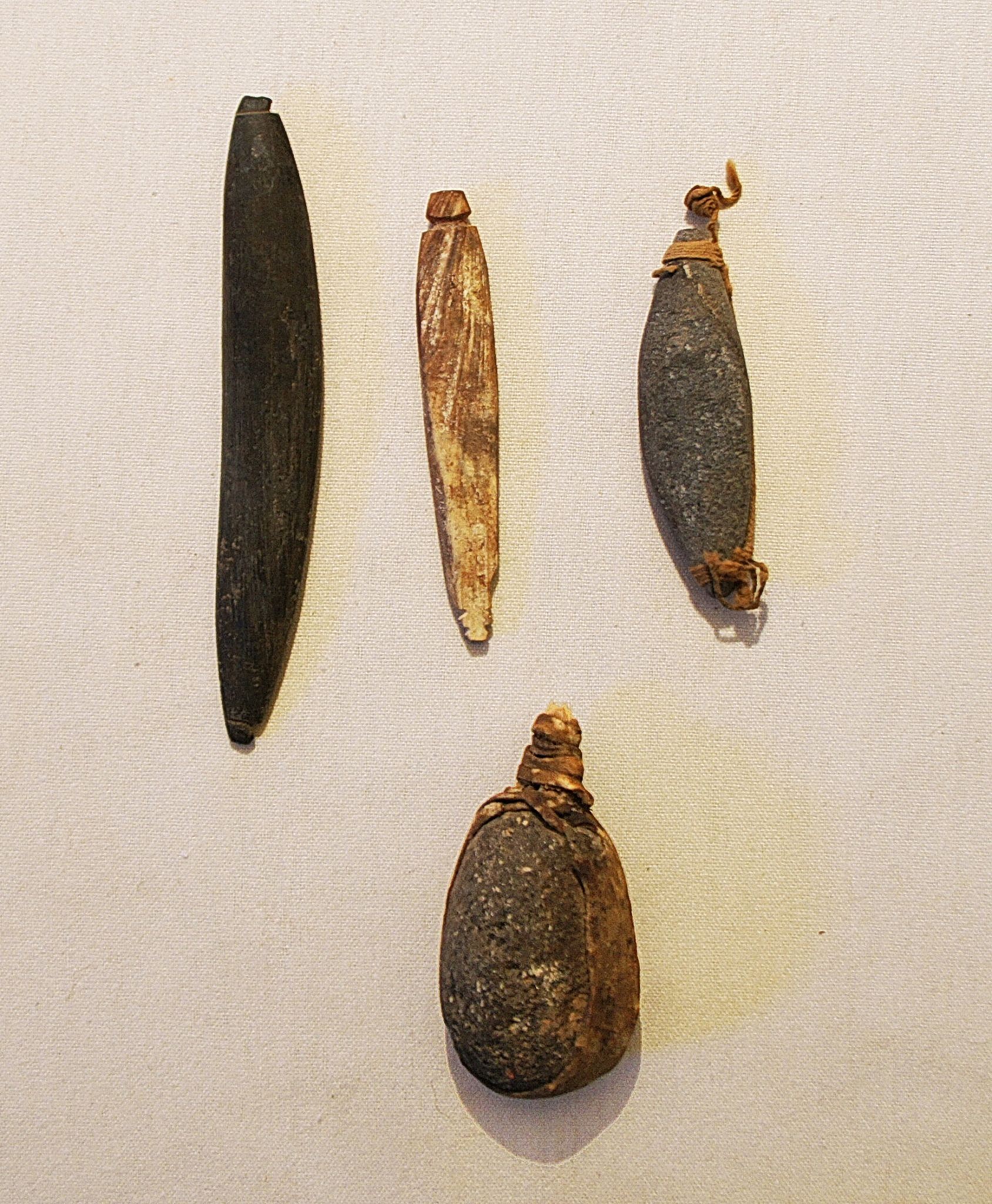 Chile, Four Fishing Sinkers With Attachments
This kit includes: one long stone sinker with a notch at each end, one bone sinker with a notch at each end, one stone sinker with the original cotton cord at each end, and one bulbous stone sinker with the original gut wrapping intact.
Period: Chile, Arica, Far North Coast, c. AD 900 - 1200
Media: Stone
Dimensions: Lengths vary: 1.25" - 2.5"
n6036