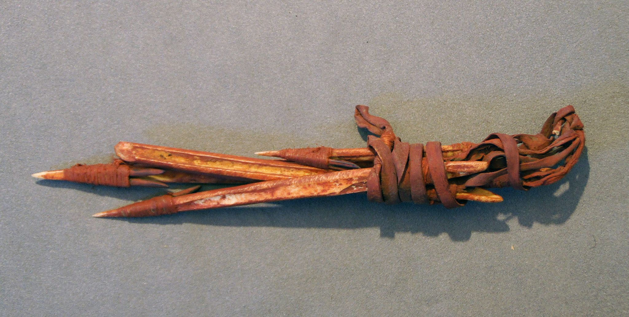 Chile, Four Bone and Thorn Harpoon Forepoints Lashed Together with Leather
Small harpoon forepoints covered in red pigment and lashed with leather.  This bundle was buried for the afterlife and was probably a fisherman's set.
Media: Bone
Dimensions: Length: 8"
n6039