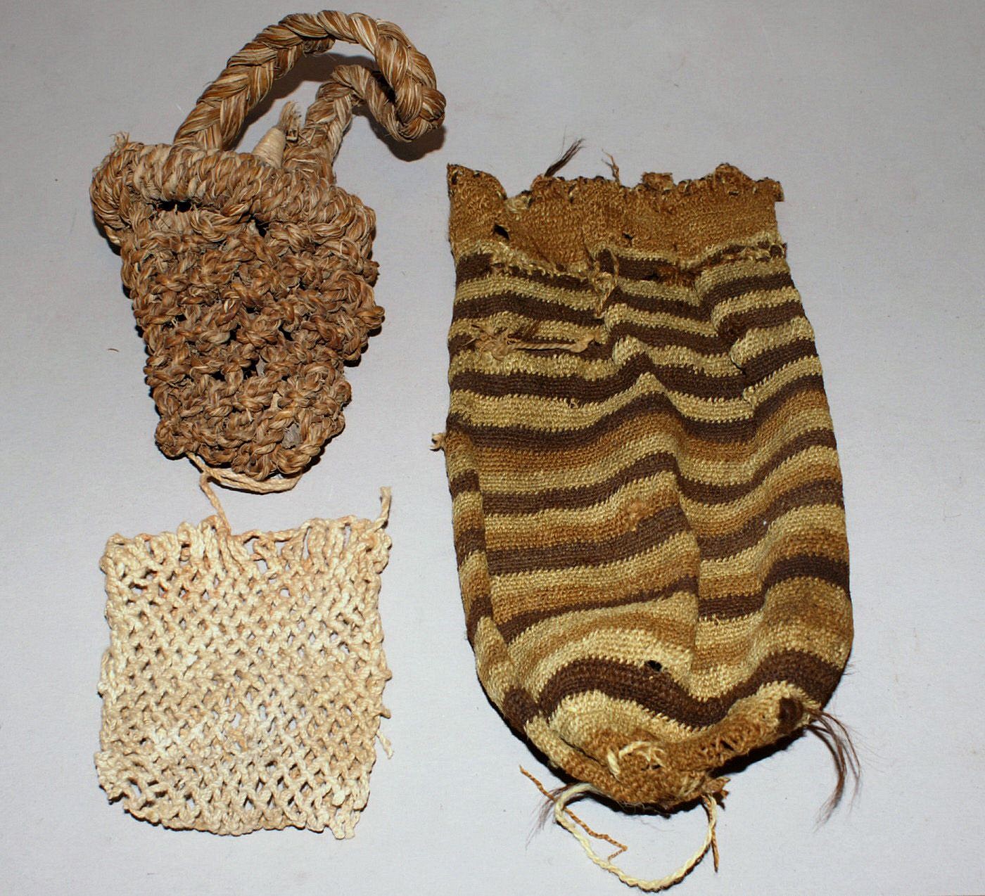 Chile, Three Types of Bags used by Fisherman
The bag with the handle is made of hemp, and would have been used for storing tools.  The white cotton bag was used to store bait for small fish.  The striped bag was made of wool with a draw string on top and a mesh on the bottom.  This bag would have been used for holding small fish.   Each bag was made with a different weaving technique.
Period: Chile, Arica, Early formative period, Alta Ramirez, c. AD 600 - 900
Media: Textile
Dimensions: Lengths vary:  3"-8"
n6045