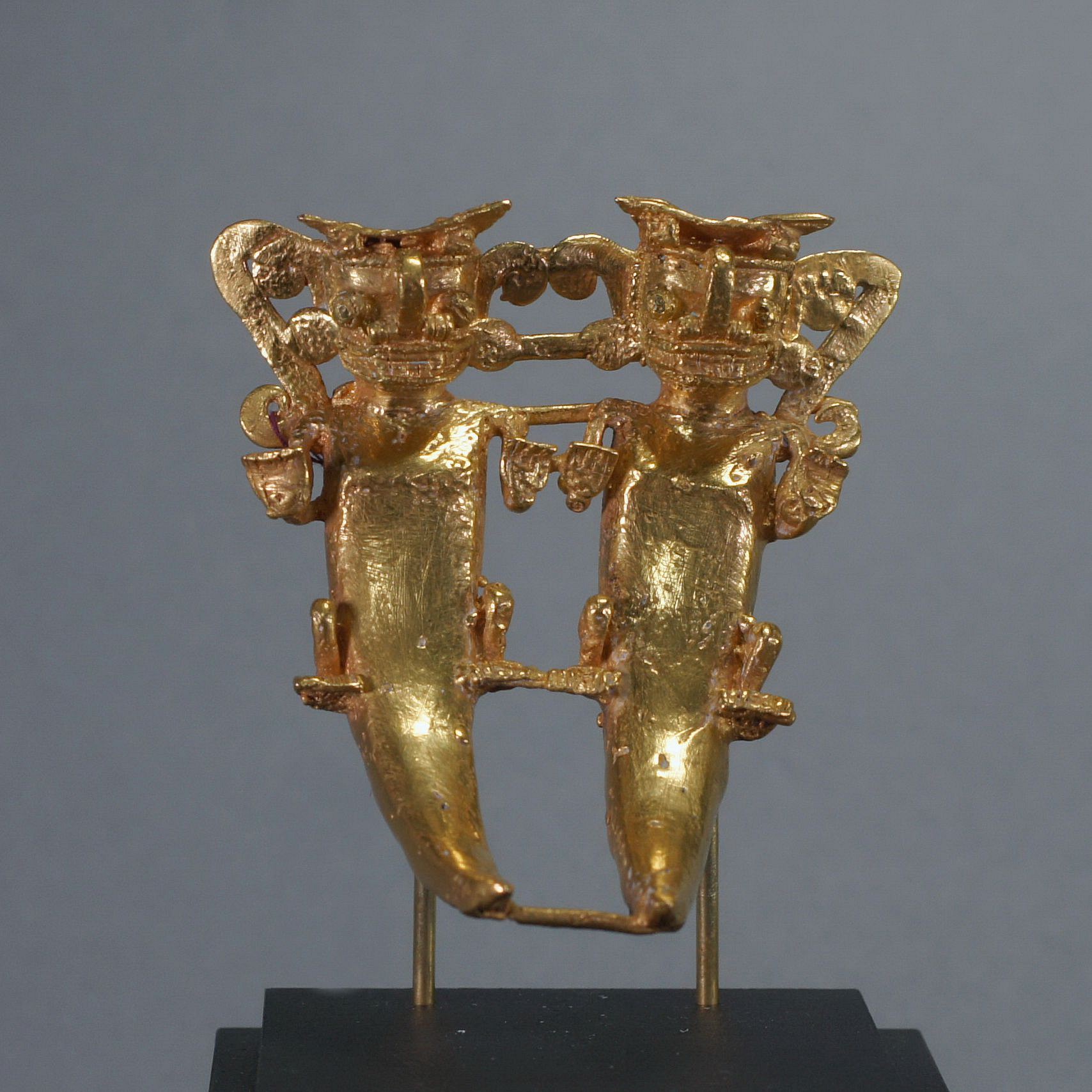 Panama, Cocle Cast Gold Pendant of Pair Anthropomorphized Bats
Lost Was cast depicting paired figures with bat faces, human hands, and a corcodilian body and tail. Duality was a known belief of the natural world: male and female, night and day, heaven and earth. Bats are nocturnal creatures and ruled the darkness.  There are two cast suspension loops behind each outside shoulder. Ex. New York collector, prior to 1970.
Period: Panama, Disquis, c. AD 1200 - 1500
Media: Metal
Dimensions: Width 2 3/4" x Length: 3 1/8"  Weight 100.6 gramsXRF
Price Upon Request
n7027
