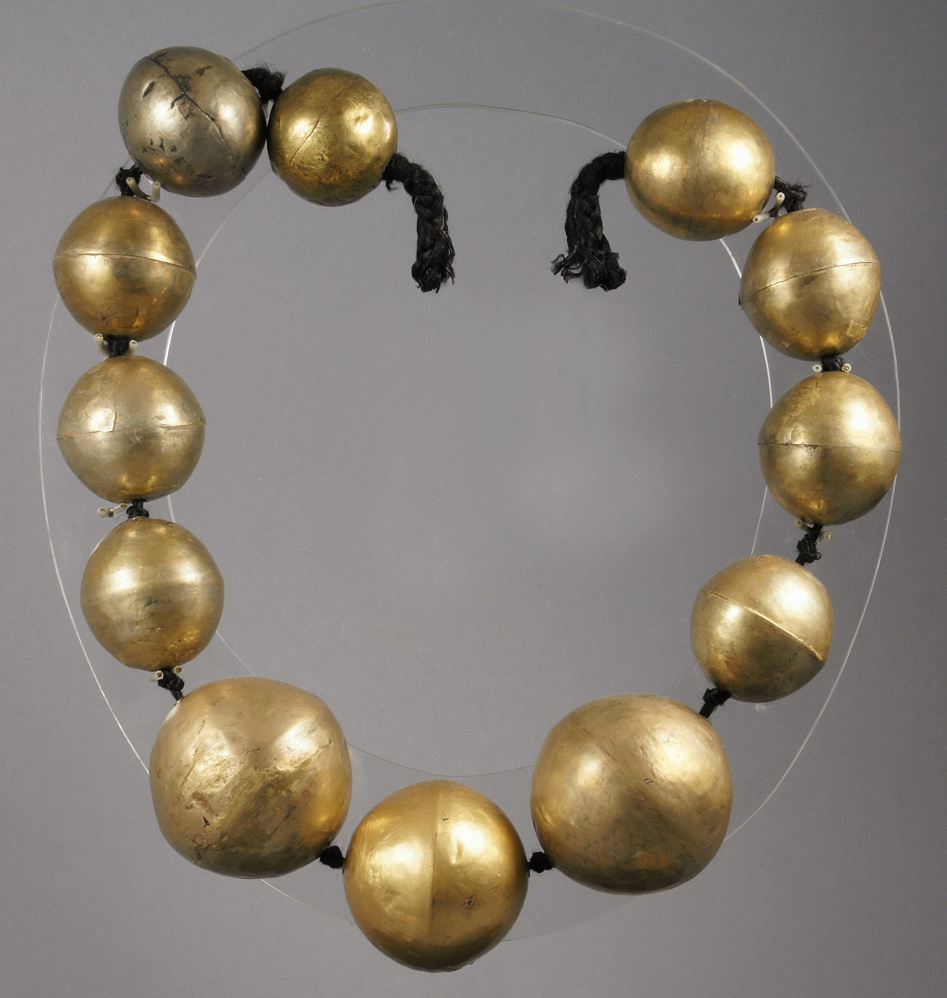 Peru, Chimú Gold 29" Necklace of Large Hollow Beads
The Chimú inherited a taste for hollow gold bead necklaces from their Moche predecessors. In both cultures, each bead was cast and hammered in two halves that were then joined together by soldering. In the Chimú technique, the edges of the two halves were nested together.  These beads are extremely light with a greater percentage of silver than gold.  They used depletion gilding to bring the gold to the surface by using of heats and salts.    This allowed the Chimu to make the gold available for a large and growing ruling class. Private Florida collection prior to 1980.
Media: Metal
Dimensions: Necklace Length: 29"; largest bead 2 1/4" diameter - smallest 1 1/2"
$27,000
M7991