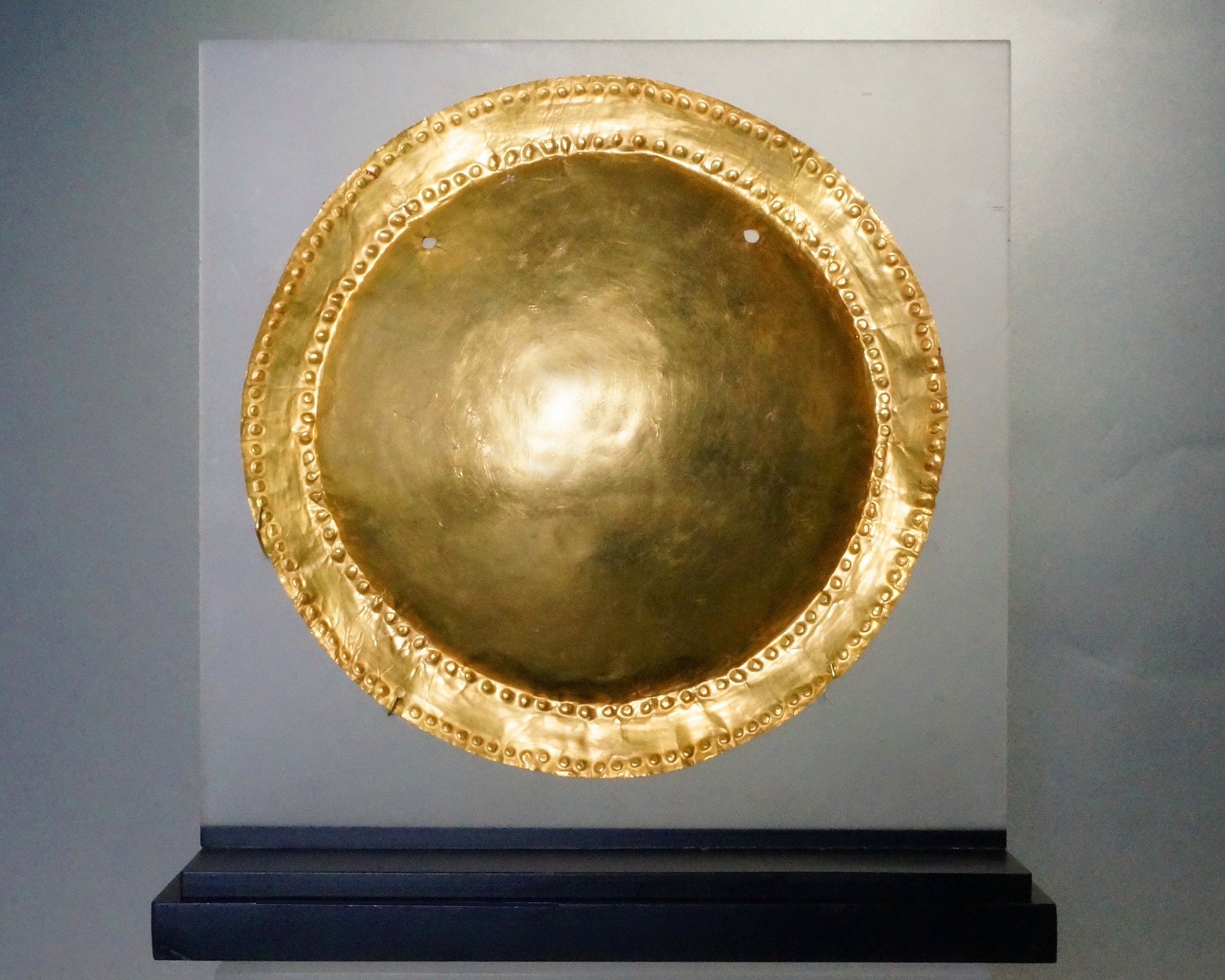 Panama, Macaracas (Cocle) Circular Gold Disc With Concave Center
The disc is embellished with two bands of small bosses on the narrow rim.  There is a pair of suspension holes.   On Columbusâ€™ 4th voyage off the coast of Panama, he and his men saw Indians wearing "Mirrors of gold." Illustrated in THE ART OF PRECOLUMBIAN GOLD, p. 119. Ex New York collector, prior to 1970.
Period: Panama, Macaracas, c. AD 800 - 1000
Media: Metal
Dimensions: Diameter 5 3/8"     24.6 Weight: grams
Price Upon Request
n7058
