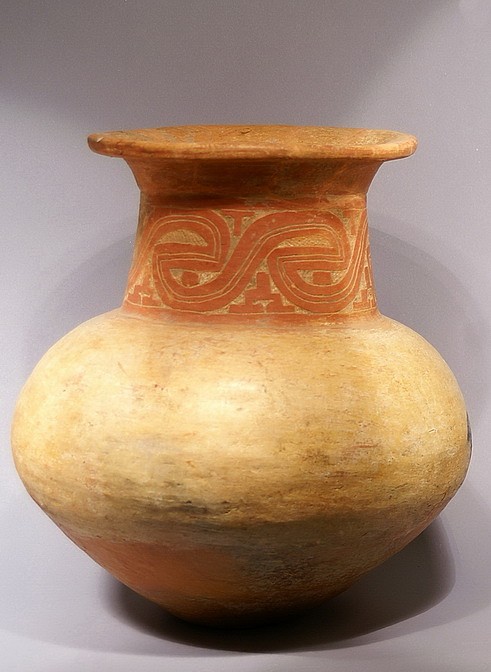 Brazil, Marajo large ceramic bichrome vessel with incised neck
This large ceremonial urn/vase is globular in form and tapers at the base. The neck is long and incised with a scroll pattern and fluted rim. The incised scroll design on the neck is a common motif in Marajoara art. Zoomorphic in character, theses scroll designs appear on the bodies of both humans and animals and on representations of clothing and furniture such as stools. Because of their similarity to painted patterns that have ritual significance in the art of remaining descendants of the culture, some interpretation of their symbolic significance can be reached. Sometimes they are referred to as "spirit" designs according to shamans who during drug induced trances report the appearance of these markings upon the bodies of ancestral spirit people. With the possible exception of certain elite groups, the Marajoara peoples tended not to decorate their common household objects.  However, they took great care to elaborate objects of ceremonial function such as funerary urns used as receptacles for the remains of the deceased. Although the actual function of this vessel is not known with certainty, it is too sophisticated in both form and decoration to have been merely utilitarian, but too small to be used as a burial urn. It is reasonable to assume, however, that it was used in a feasting ceremony. This jar has a smudge stain from the firing process on one side. Several examples of similar style and iconography are illustrated and discussed by Anna C. Roosevelt in "Moundbuilders of the Amazon: Geophysical Archaeology on Marajo Island, Brazil", San Diego, Academic Press, Inc, 1991.
Media: Mixed Media
Dimensions: Height:  16"
$17,500
MM069