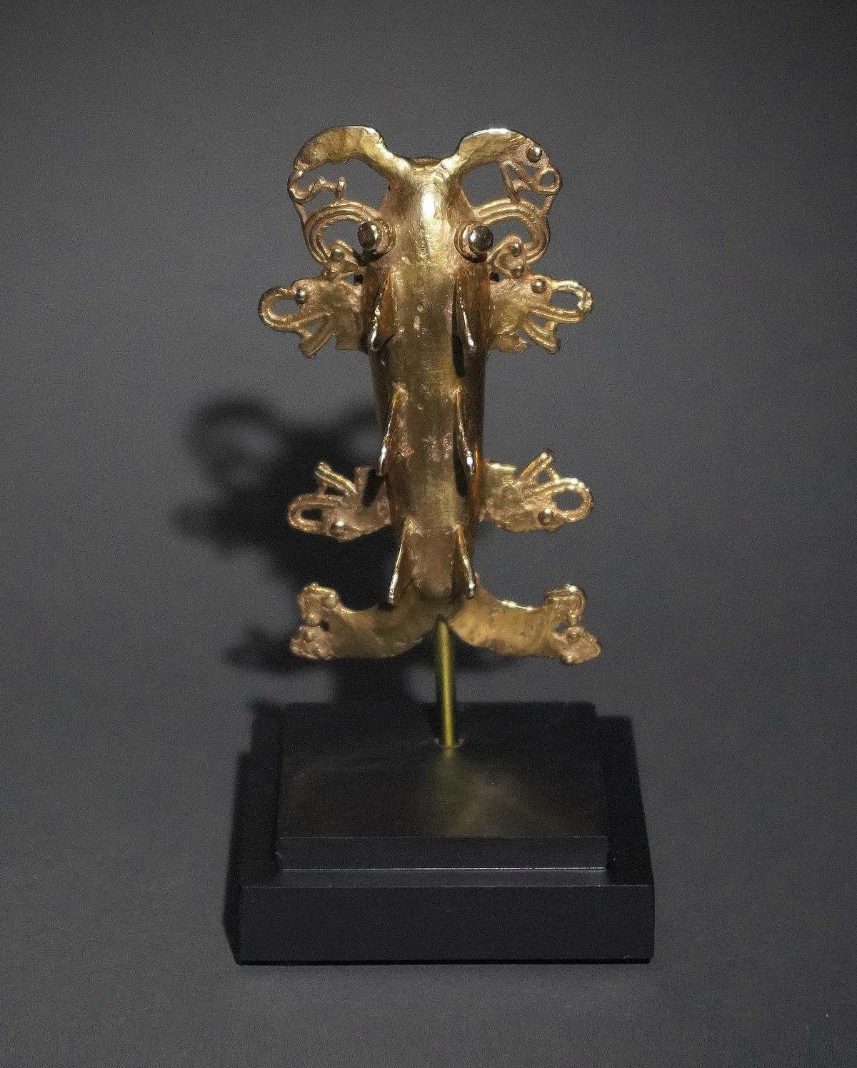 Panama, Veraguas Cast Gold Shark with Serpent and Crocodile Appendages
This is a variation of the classic Veraguas shark, with three sets of dorsal fins and four sets of Saurian appendages.  On the underside of the mouth are two rows of intricately modeled teeth.  There are two suspensions loops underneath the mouth.  From the Jan Mitchell collection, prior to 1970, by descent to his sons.
The top left serpent appendage is missing its eye.

Media: Metal
Dimensions: Length: 3 1/4" x Width: 1 7/8" Weight: 65.5 grams.
Price Upon Request
p1046