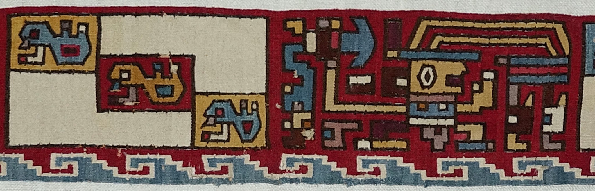Peru, Huarmay Tapestry Border to a Poncho with Three Warriors
This classic Huarmay style tapestry is crafted in the classic Huarmay colors of ivory, blue, and red with black outlines.  Each warrior wears different colors, and each holds a tumi in his left hand and wears an elaborate headdress with two long, forward-tilting plumes.  Separating the warriors are blocks of ivory with three abstract birds on a diagonal.  Along the bottom edge is a repeating classic step volute line in blue with a white outline.  The Huarmay culture thrived during the Late Moche Period on the most Southern of the fourteen Moche valleys, and were influenced by the Wari.  Mounted, in a Plexiglas box.  Minor losses to the ivory central panel. Formerly in a New York private collection prior to 1979.
Media: Textile
Dimensions: Width: 48" x Height: 6 1/2"
$8,500
n9040