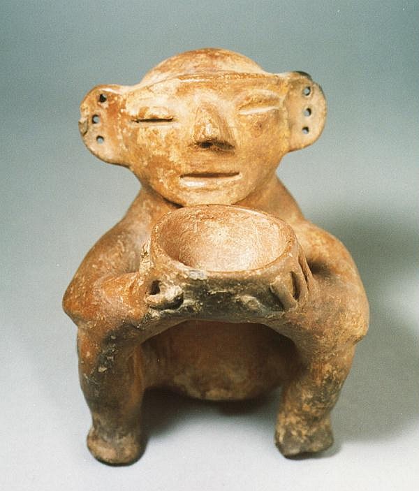 Ecuador, Ecuadorian Ceramic Seated Figure Holding a Bowl
This beautifully serene, meditative figure, perhaps a shaman, is seated in a restive position and offering a bowl.  This bowl was perhaps used to inhale tobacco smoke or for drinking a ritual alcoholic or psychedelic libation.  The historical record of the ancient Andes indicates shamanic use of mind-altering substances for religious rituals.   A similar example is illustrated in
Meggers Evan’s Archeological Investigations on The Rio Napo.
Media: Ceramic
$2,000
88203