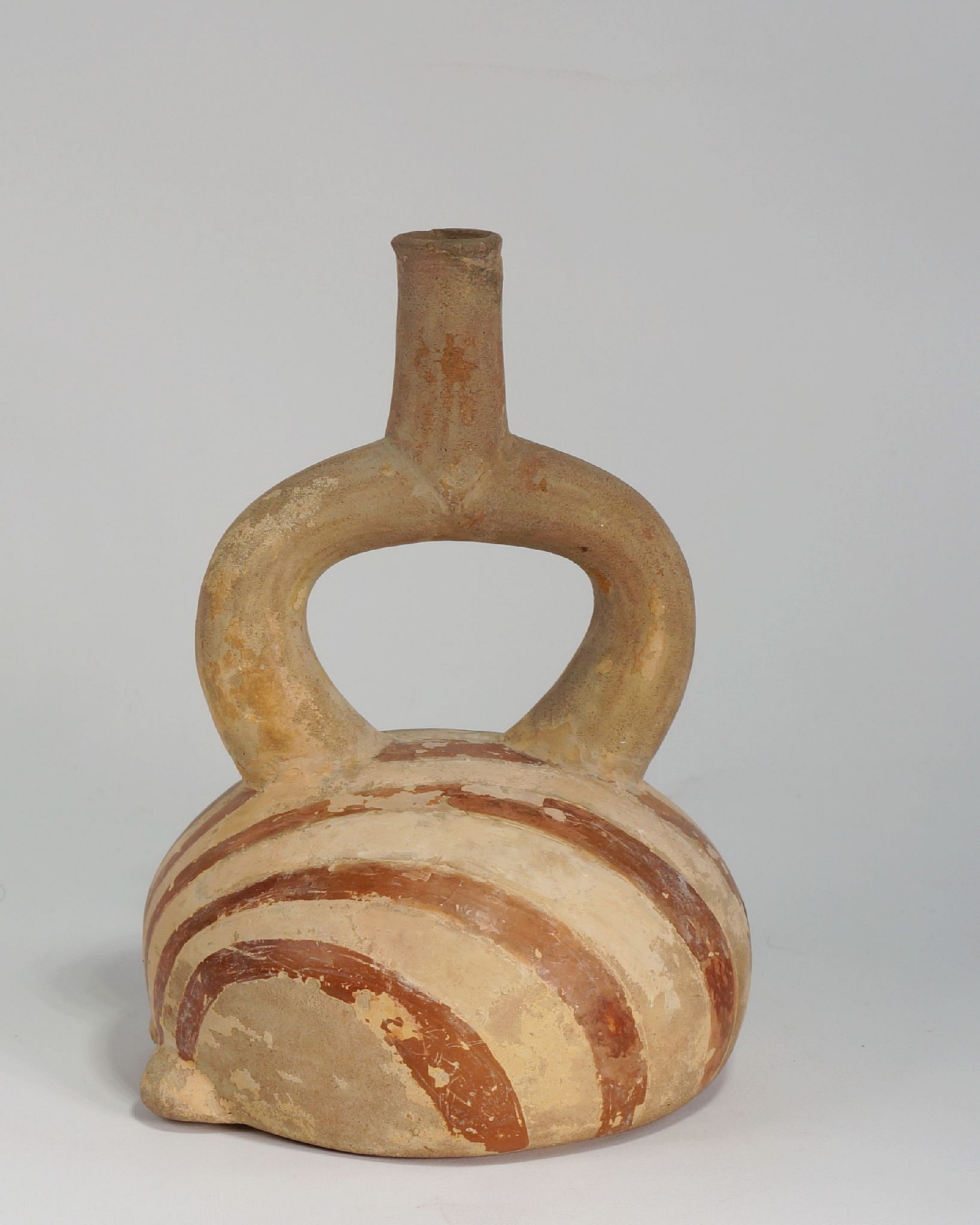 Peru, Stirrup Spout Vessel Depicting a Scallop
This elegant vessel is modeled after the Argopectin purpuratus (the Peruvian calico scallop).  It is decorated with swirling painted stripes in brown slip on a cream ground and is a typical example of Moche realism.  During El NiÃ±o events, bivalves proliferate along the coast; scallops are the most abundant species.  The bivalves, in turn, attract octopi, which feed almost exclusively on these mollusks.  Octopi are a frequent theme in Moche art.  A similar example of a stirrup spout vessel in the form of a bivalve shell is illustrated in The Spirit of Ancient Peru: Treasures from the Museo Arqueologico Rafael Larco Herrera, edited by Kathleen Berrin (1997: fig. 41).
Media: Ceramic
Dimensions: Height 7"
Price Upon Request
95065
