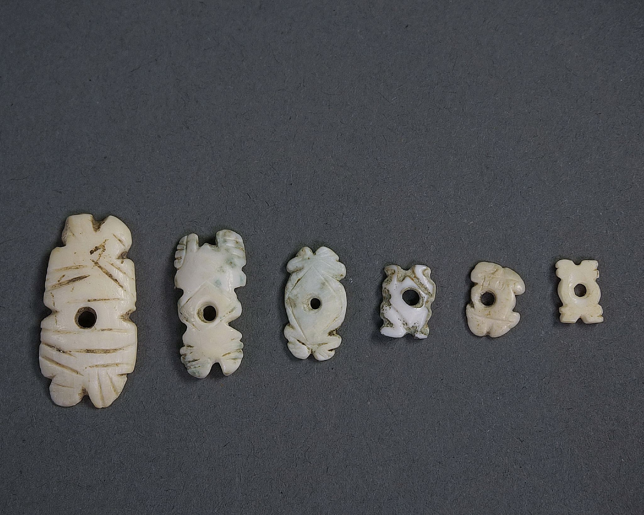 Dominican Republic, Six Taíno  Miniature Shell Abstract Frog Ornaments
These extremely delicate miniature appliquÃ©s likely belonged to a larger set that would have covered the cape of a chieftain, or they may have been elements to a necklace or bracelet.  The Taíno  conquered their neighbors on the Turks and Caicos Islands in the Bahamas to obtain the best shells in the region, for the production of jewelry.  At least one archaeological site there has been identified as a craft village.
Period: Dominican Republic, Taíno , c. AD 1000 - 1500
Media: Shell
Dimensions: Height Range: 3/8" to 7/8"
99357