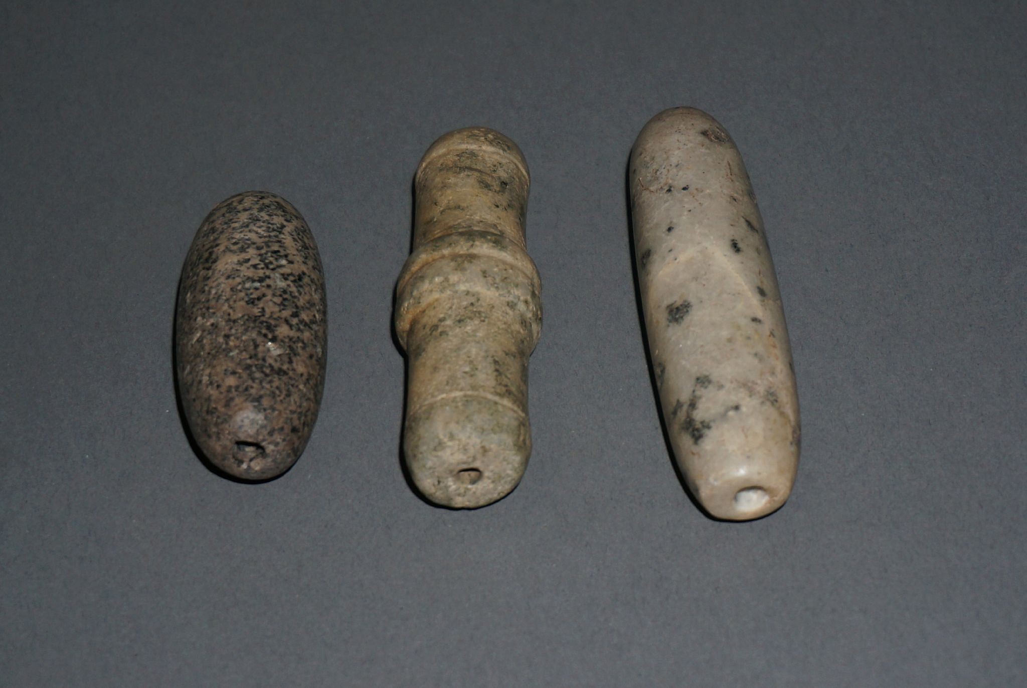 Dominican Republic, Three Long Taíno  Stone Beads
These unusually large and heavy stone shaped beads would have required great skill to be able to drill.  These beads represent a variety of types of shapes, from slender to ribbed and tapered.  Such large beads would have been reserved for high status individuals.
Period: Dominican Republic, Taíno , c. AD 1000 - 1500
Media: Stone
Dimensions: Length: 2" to 3.5"
99378