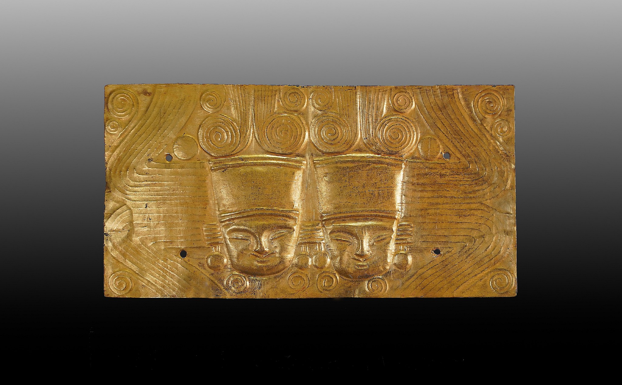 Colombia, Calima Gold Hammered and Incised Plaque with Two Royal Heads
In ancient Pre-Columbia, twin imagery was considered to represent good luck and prosperity.  This incised gold plaque features twin royal figures, identifiable by their headdresses and the elaborate swirl design above their heads, indicating that they are individuals of high status.
Period: Colombia, Calima, c. AD 700 - 1200
Media: Metal
Dimensions: Height: 3  1/2" x Width: 6 1/2" Weight 28.8 grams.
$24,000
p5051