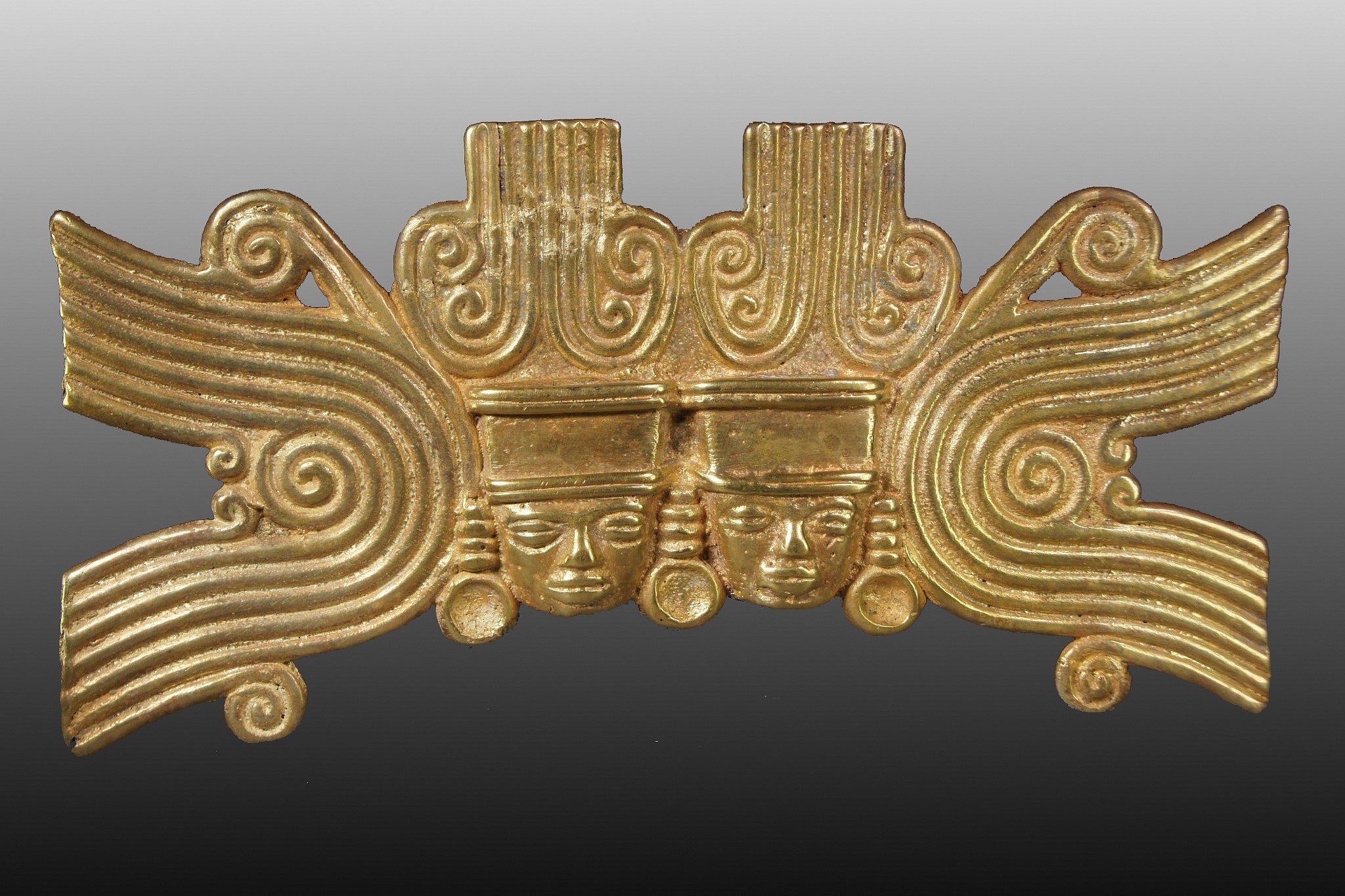 Colombia, Large Cast Gold Sinu Pendant with Two Royal Faces
This unique pendant features classic Quimbaya iconography.  The design depicts twin faces side by side, wearing crowns and earring ornaments, with large spirals framing the twin faces on both sides.  Twins were considered lucky in Pre-Columbian cultures.  On the back are a pair of vertical suspension tubes.  This ornament was found in the Uruba region on the Panamian border, an area of varied trade with neighboring cultures, especially the Sinu, Darien, and Quimbaya. Formally in the collection of a private Texas collector, prior to 1970. The top of upper right plumb was broken and soldered back together. Acquired from a Texas collector.
Period: Colombia, Gulf of Uruba, c. AD 500 - 1000
Media: Metal
Dimensions: Height: 4 1/4" x Width: 8 5/8"  Weight: 282 grams.
$167,500
N6004